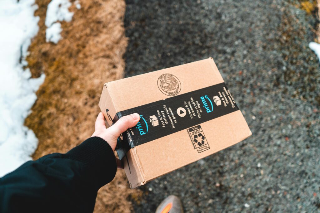 Delivery driver carrying an Amazon Prime package, symbolizing the importance of accurate and up-to-date product information for Amazon listings.