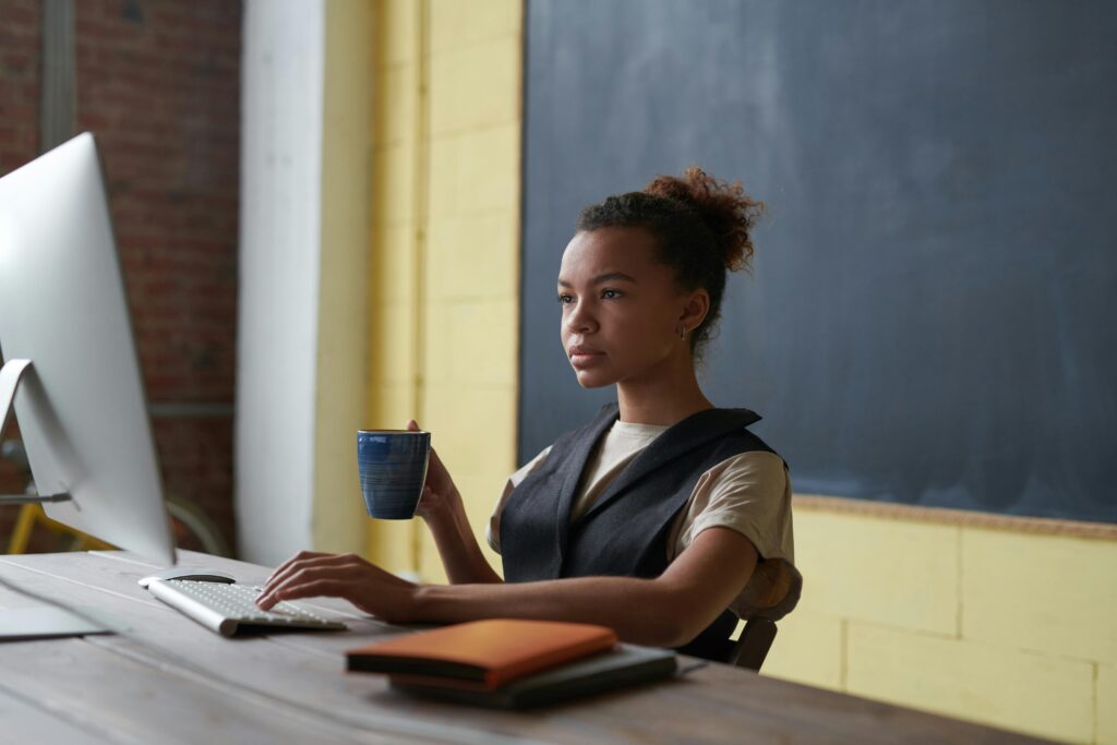 Woman working at her laptop while holding a mug, symbolizing the efficient creation and management of technical product data sheets using a PIM system.