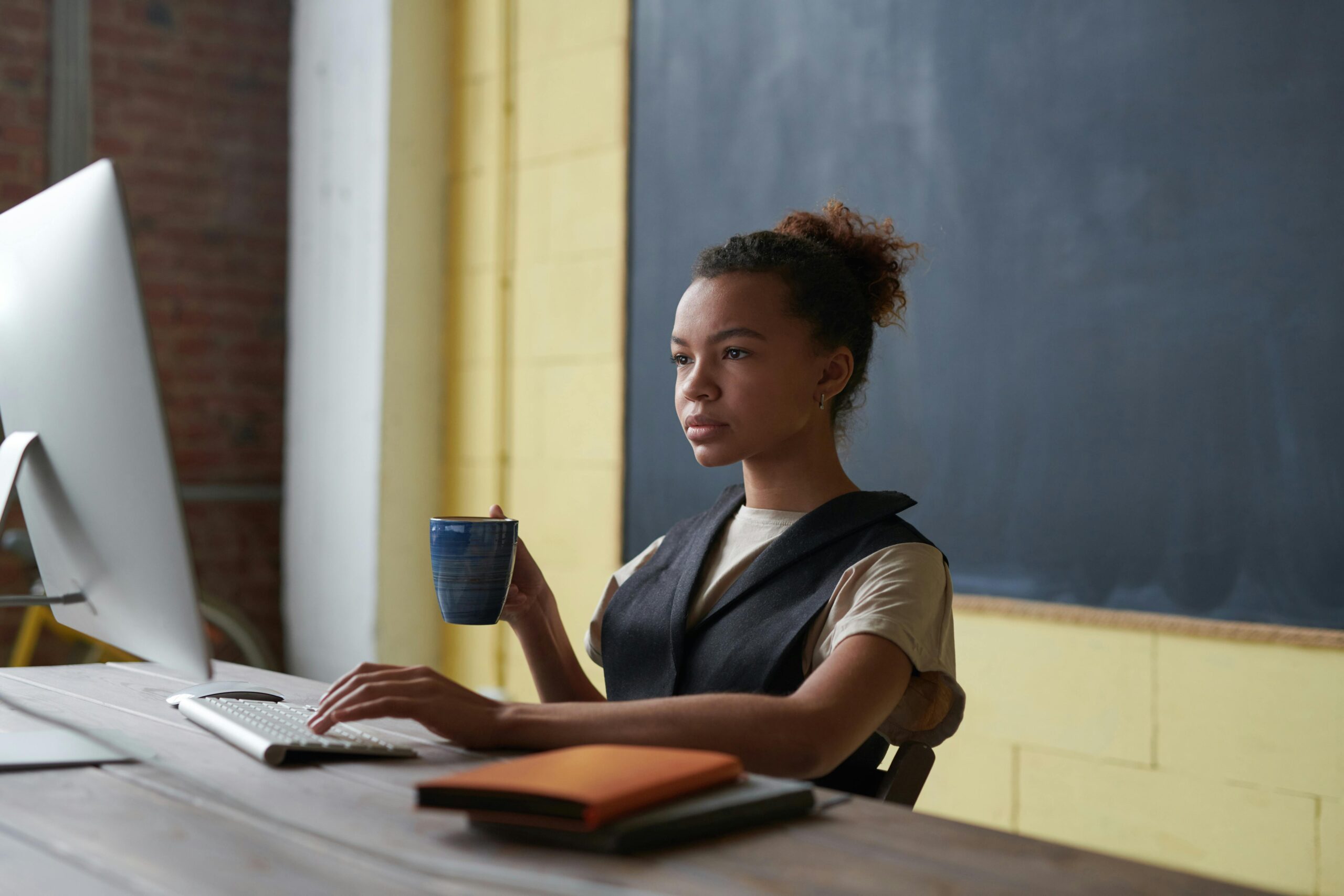 Woman working at her laptop while holding a mug, symbolizing the efficient creation and management of technical product data sheets using a PIM system.